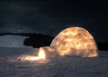Kış dağlarında ışık saçan gerçek bir eskimo evi.