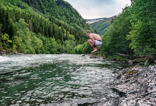 Muž skočí do studené horské řeky — Stock fotografie