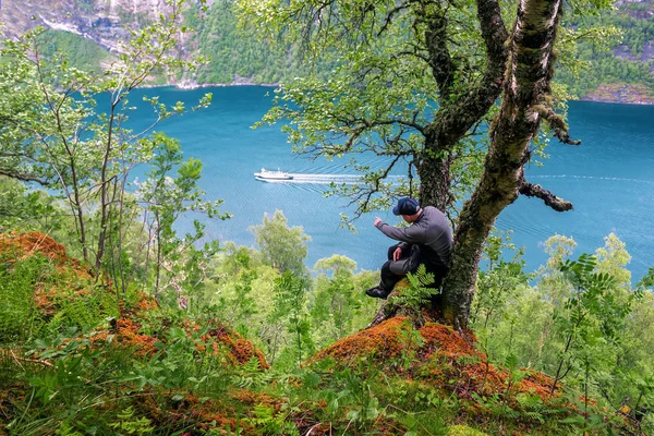 Ein Mann sitzt auf einem Baum über einer hohen Klippe — Stockfoto