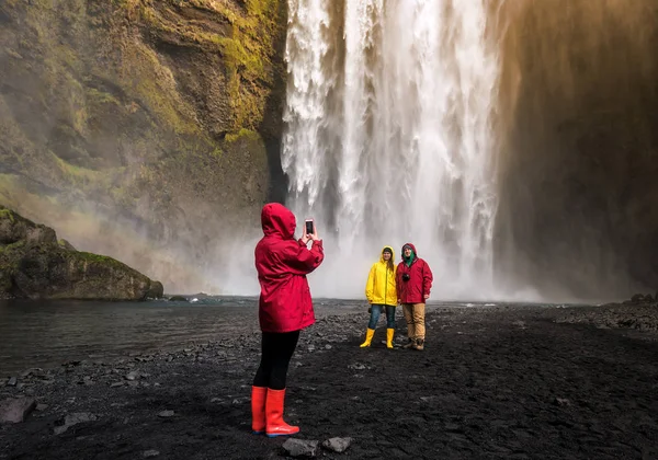 Amigos son fotografiados antes de una cascada en Islandia —  Fotos de Stock