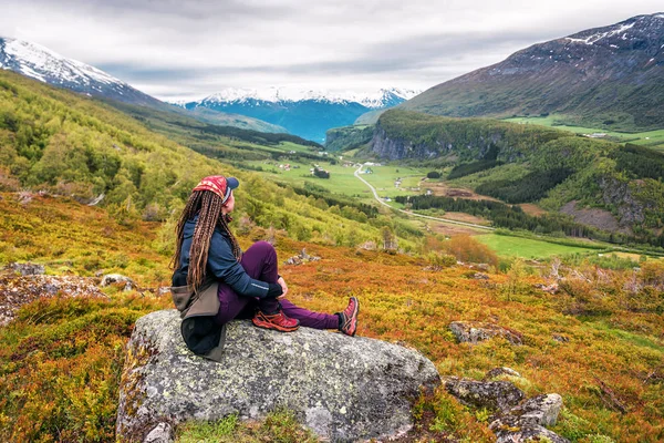 Turistická dívka s dredy sedí na skále — Stock fotografie