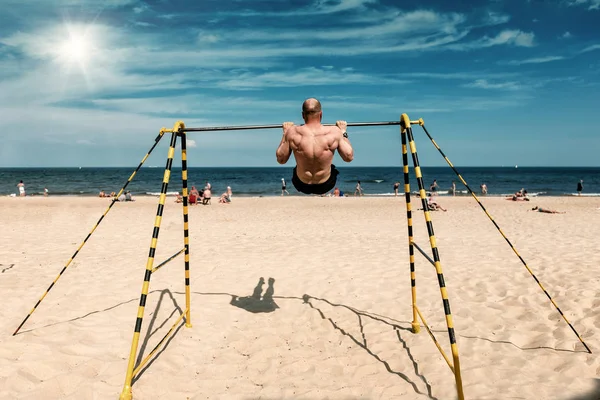 Homem esportivo fazendo exercícios no bar da praia no verão — Fotografia de Stock