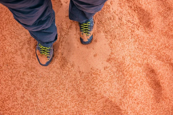 Férfi túracipőben áll a vörös homokon — Stock Fotó