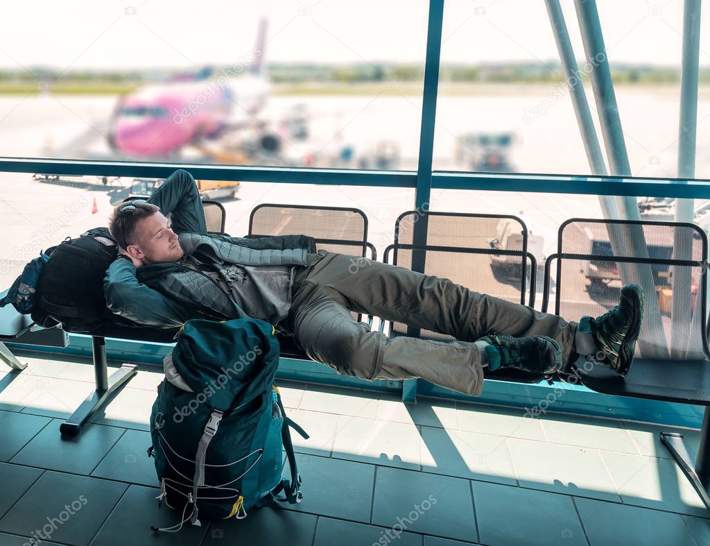 young man with backpack sleeps in the airport