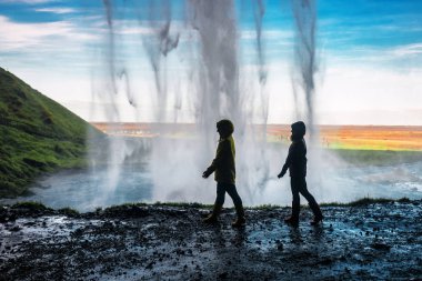 two girls walking under a waterfall clipart