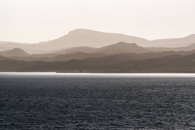Akabe 'deki sisin içinde deniz ve gri dağlar sıralanır. Ürdün. İsrail 'de Görünüm