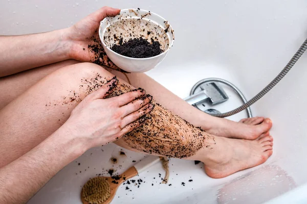Woman cleans her feet with coffee scrub. Health and spa theme