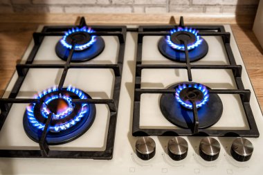 Closeup shot of blue fire from domestic kitchen stove top. Gas cooker with burning flames of propane gas. Industrial resources and economy concept. clipart
