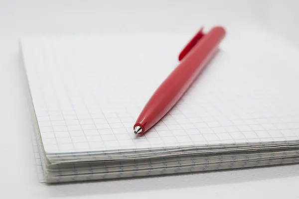 Beyaz defter ve beyaz zemin üzerine kırmızı kalem