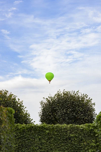 Green balloon flying in the sky above the park