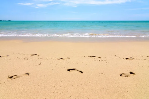 Footprint on the beach with blue water and sky on background,