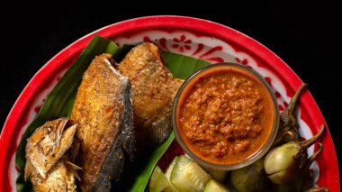 Kızarmış uskumru ve biber ezmesi sebze tabağında.