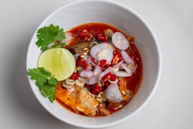 Sardalya ve domates soslu salata beyaz bir fincanda, üst köşeye yakın..