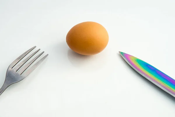 Steel dining fork in the egg shell and butter knife on a white background closeup — Stock Photo, Image