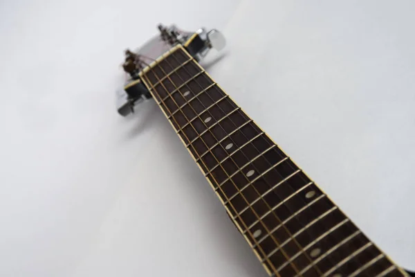 Na kytaru a na bílém izolovaném pozadí je na kytaře nahoře výhled na hrdlo kytary. Perspektiva akustické kytary na šachovnici — Stock fotografie