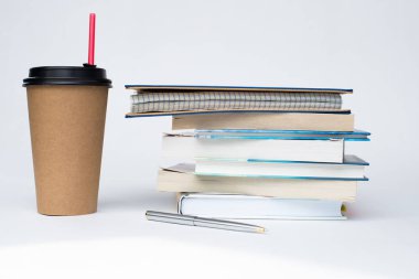 kırmızı bir saman ile bir kağıt Fincan kahve beyaz bir arka plan üzerinde kitap yığını yanında duruyor