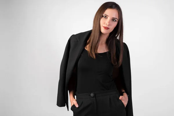 Beyaz arka planda güzel bir kızın portresi, omuzlarına siyah bir ceket, düz siyah saçlar, seksi bir görünüş.,