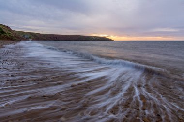 deniz dalgaları yollar ile. dalgalar hareket göstermek için düşük çekim nedeniyle yumuşak odak. Filey beach, North Yorkshire, İngiltere.