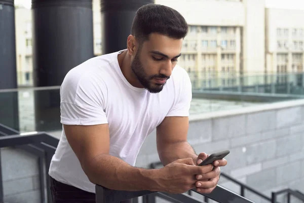 Attractive young man typing on the phone. Front view.