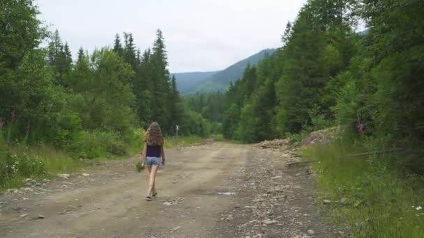 Pige går på vejen i skoven med bær – Stock-video