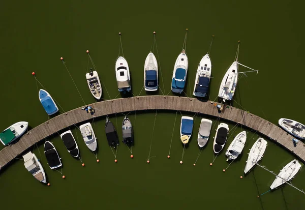 Aerial View by Drone of Yacht Club and Marina. Top view of yacht club. White boats in sea water. Marina dock yachts and small motor boats. Yacht and sailboat is moored at the quay. Parking