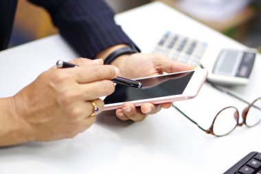 Modern ofisteki iş hakkında konuşmak için elinde cep telefonu tutan Asyalı aktif kadın..