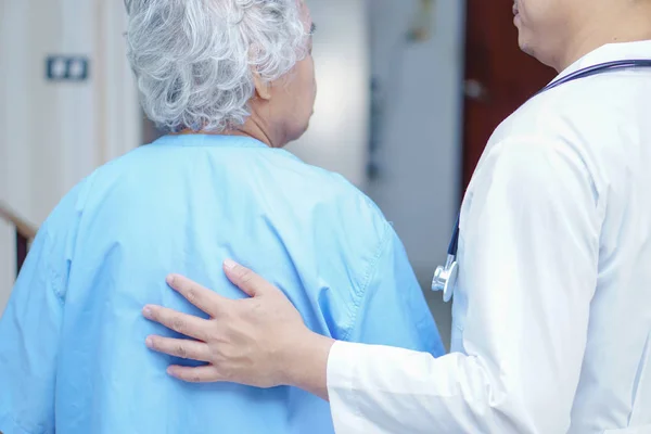 Doctor touching Asian senior or elderly old lady woman patient with love, care, helping, encourage and empathy at nursing hospital ward : healthy strong medical concept