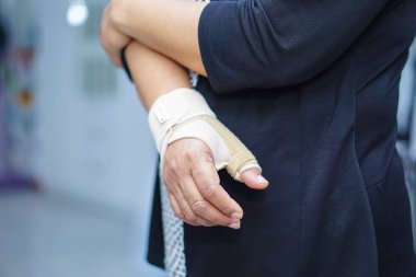 Asyalı orta yaşlı bayan kadın ofiste el ve parmak De Quervain sendromu tedavisinde elastik bandaj kullanın.