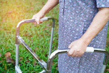 Asya 'lı yaşlı ya da yaşlı kadın tatilde parkta yürürken sağlıklı yürüyen kadın kullanıyor. 