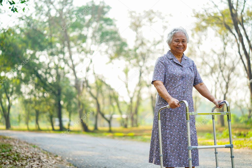 Asian senior or elderly old lady woman patient walk with walker in park : healthy strong medical concept 