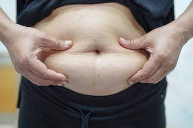 Şişman Asyalı kadın ofiste şişman göbek gösteriyor.