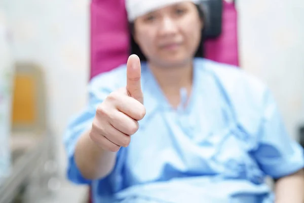 Asian middle-aged lady woman patient sitting on wheelchair with happy and bright face in the hospital ward : healthy medical concept
