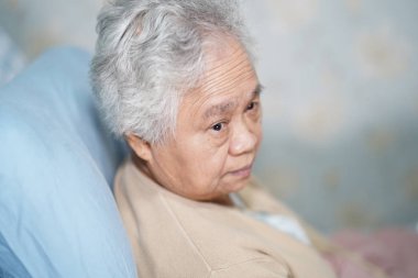 Asya yaşlı yaşlı yaşlı kadın hasta umut ile hemşirelik hastanesi koğuşunda yatakta oturan ve onun akrabası bekliyor : sağlıklı güçlü tıbbi kavram