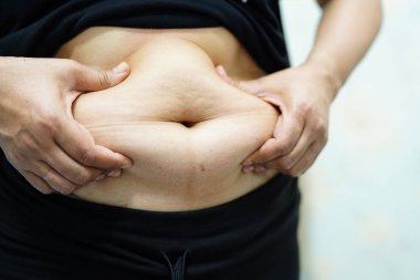 Şişman Asyalı kadın ofiste şişman göbek gösteriyor..