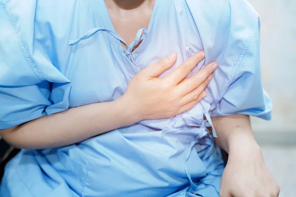 Asian middle-aged lady woman patient chest pain may be a symptom of a heart attack in the hospital ward : healthy medical concept