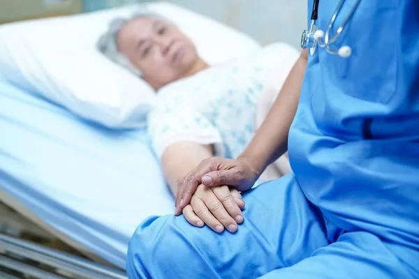 Asian nurse physiotherapist doctor care, help and support senior or elderly old lady woman patient lie down in bed at hospital ward : healthy strong medical concept