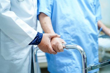 Asya hemşire fizyoterapist doktor bakımı, yardım ve destek yaşlı veya yaşlı yaşlı kadın hasta hastane koğuşunda walker ile yürümek: sağlıklı güçlü tıbbi kavram