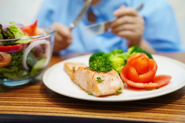 Asian senior or elderly old lady woman patient eating breakfast healthy food with hope and happy while sitting and hungry on bed in hospital