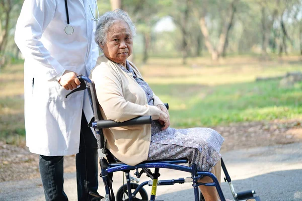 Doctor help and care Asian senior or elderly old lady woman patient sitting on wheelchair at park in nursing hospital ward : healthy strong medical concept