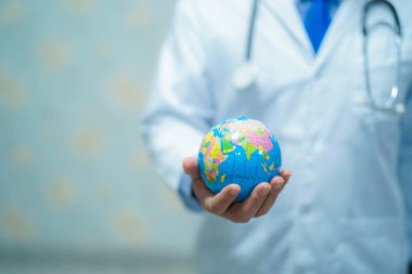 Dünya küresi tutan Asyalı akıllı adam doktor: sağlıklı güçlü tıbbi konsept.