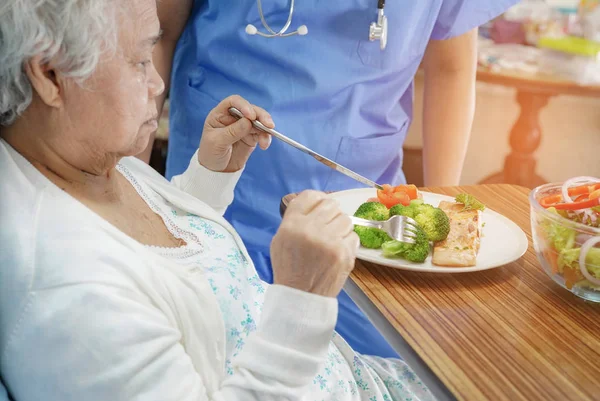 Asian senior or elderly old lady woman patient eating breakfast healthy food with hope and happy while sitting and hungry on bed in hospital