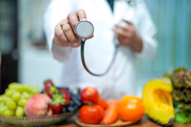Çilek, patates, elma, Erik, üzüm, havuç, şeftali, kabak ve salata ile portakal suyu tutan beslenme uzmanı Doktor öğretim sağlıklı gıda güçlü hastaya masasında sebze