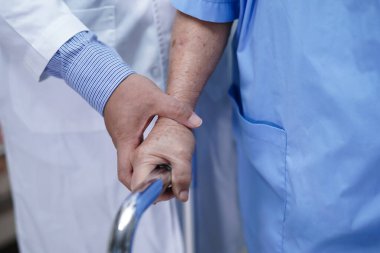 Doktor yaşlı ya da yaşlı kadın hastaların hemşire koğuşunda Walker 'la yürümelerine yardım ediyor..
