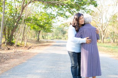 Asyalı yaşlı ya da yaşlı kadın kızına sevgi, ilgi, yardım, cesaret ve empati ile sarılıyor. 