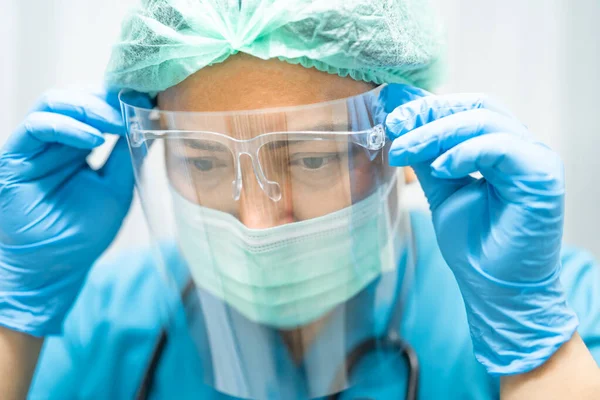 Asian doctor wearing face shield and PPE suit to check patient protect safety infection Covid-19 Coronavirus outbreak at quarantine nursing hospital ward.