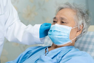 Güvenlik enfeksiyonunu korumak ve Roman Coronavirus Covid-19 virüsünü öldürmek için hastanede maske takan yaşlı ve yaşlı bir kadın..
