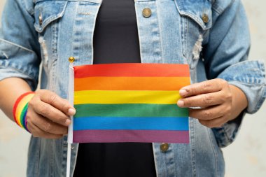 Mavi kot ceket ya da kot pantolon giyen ve elinde gökkuşağı renkli bayrak tutan Asyalı kadın, LGBT gurur ayının sembolü, Haziran sosyal ortamında eşcinsel, lezbiyen, biseksüel, transseksüel, insan hakları.