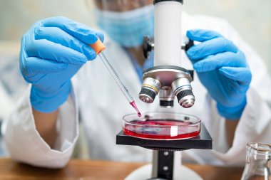 Laboratuvarda mikroskopla çalışan Asyalı biyokimyacı ya da mikrobiyolog. Coronavirus salgınını korumak için. Covid19, bakteri ve mikroplar..