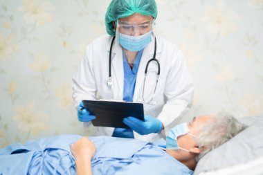 Karantina hemşire koğuşundaki Covid-19 Coronavirus salgınını kontrol etmek için yüz maskesi ve PPE kıyafeti giyen Asyalı doktor..