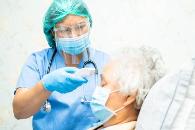 Asyalı yaşlı ya da yaşlı kadın hastanın yüz maskesi taktığını ölçmek için dijital termometre tutan doktorun hastanede ateşi var, sağlıklı ve güçlü bir tıbbi konsepti var..